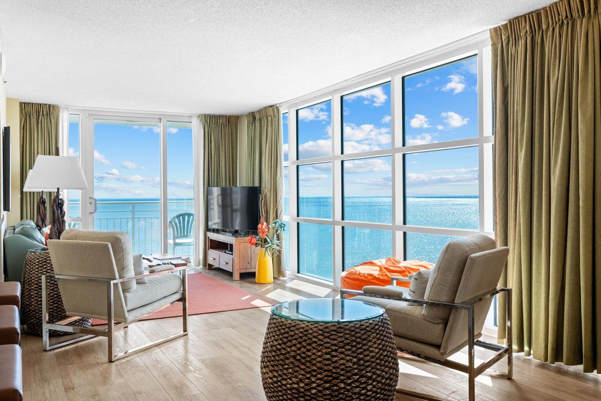 3-bedroom oceanfront corner rental showing a spacious living room with the ocean in the background through the windows