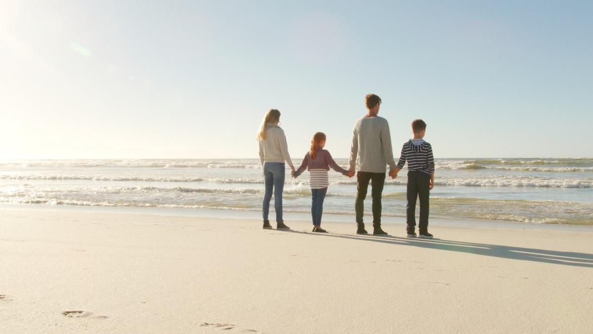Family standing on the beach looking out at the Atlantic Ocean in Myrtle Beach near Seaside Resort.