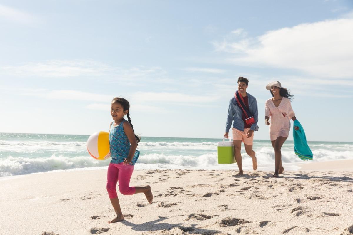Mom, Dad, and daughter walking on the beach having fun.