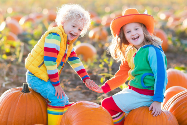 Two smiling kids in a pumpkin patch