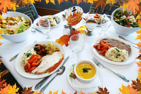 Assorted thanksgiving dinner main courses and side dishes on plates on a white tablecloth